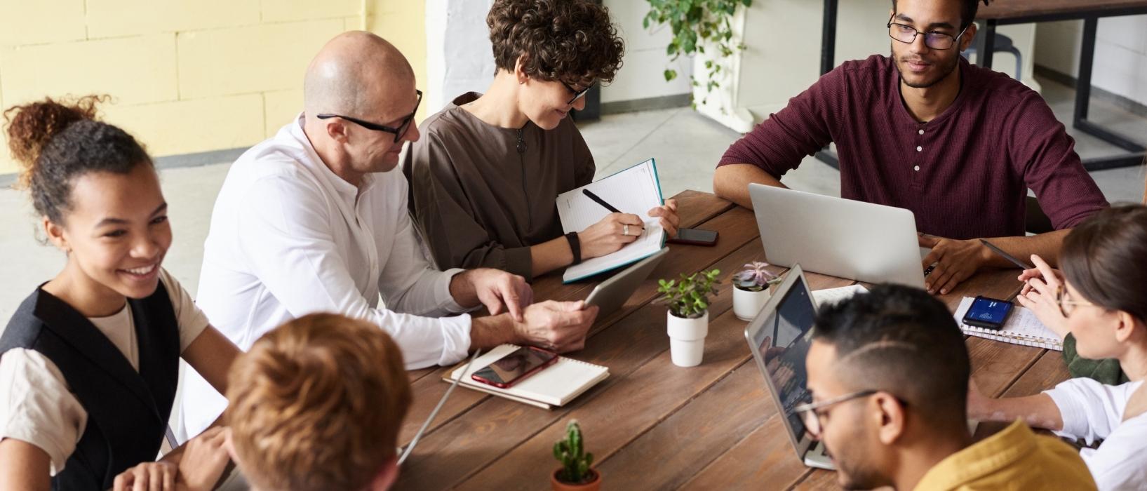 Group of employees on laptops chatting during meeting