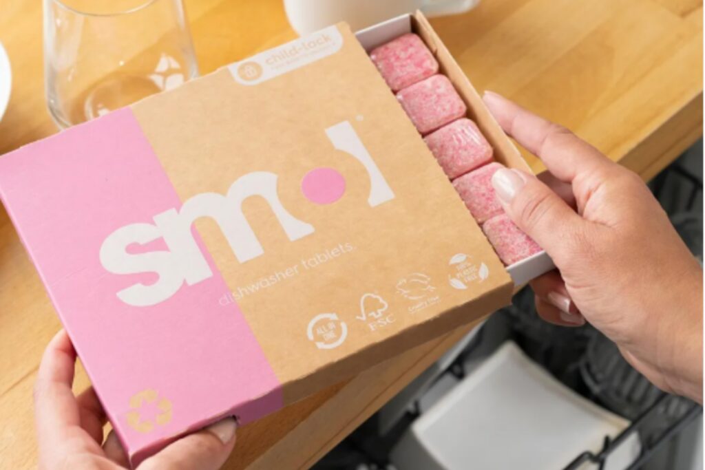 woman opening cardboard box full of Smol dishwasher tablets